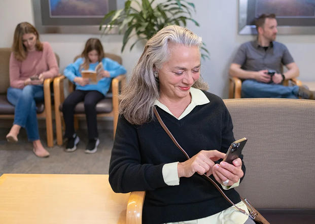 2-broll woman in waiting room completing patient intake on mobile phone