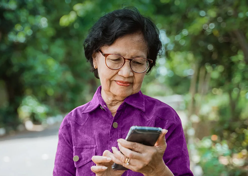 20-olderadults a photo of an older woman smiling while using a cell phone